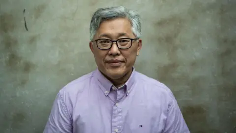 Getty Images Jin Mingri, head pastor of the Zion church, in a lilac shirt pose for a photo in September 2018, days after authorities officially banned his church
