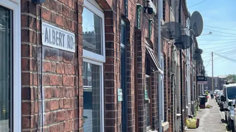 The sign for Albert Road on a long row of terraced houses