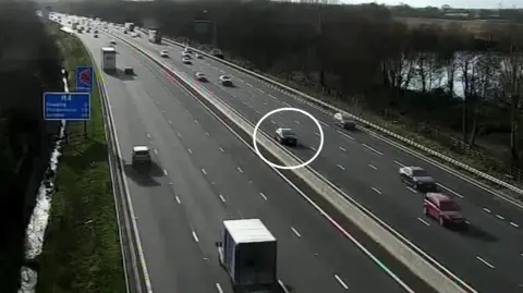 The Nissan Micra circled in white as other vehicles pass on either side of the motorway.