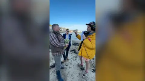 Greg from Radio 1 with the two contestants standing and looking at a tiara