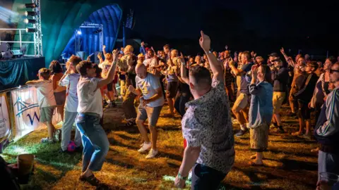 St Richard's Hospice A crowd of people are pictured dancing under bright blue and orange lights at night.