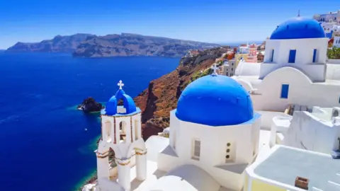 The town of Oia in Santorini, with white buildings and vibrant blue dome roofs and an amazing blue ocean