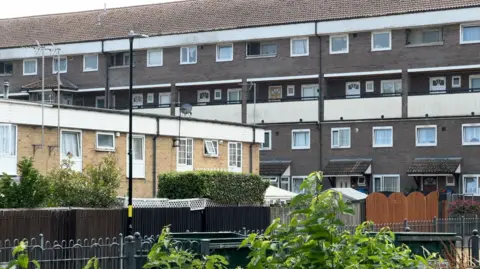 A large block of flats with grey walls and another block of flats with brown walls in the foreground