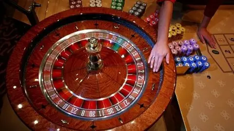 Getty Images A roulette wheel, showing the red and black numbers. There are chips in different colours to the right. A hand is visible spinning the wheel.