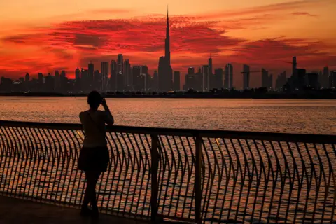 AFP A woman takes a picture of the Dubai skyline with Burj Khalifa, the world's largest building, as viewed from Creek Harbour on February 5, 2025.