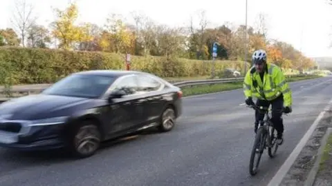 Car blurred as it overtakes cyclist