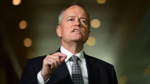 Getty A middle aged man in suit and tie gestures with his hand as he speaks