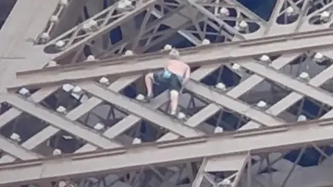 Man climbing the Eiffel Tower successful  Paris