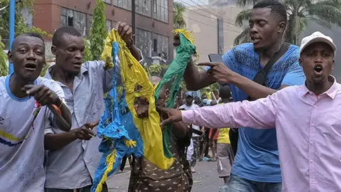 EPA Five men in Kinshasa tear apart a Rwandan flag as they shout in protest about the M23's attack of Goma in DR Congo - 28 January 2025