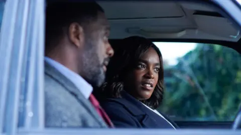 Mosaku, who is playing the role of Det Sgt Catherine Halliday in Luther, is pictured in the passenger seat of a car next to the character of Luther, played by  Idris Elba. 