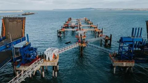 Holyhead port walkways jutting out of the sea. There is an object jutting out of the sea which seems to have broken off of the port.