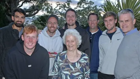 Somerset County Cricket Club Mary Elworthy-Coggan is standing in between cricket players. They are all smiling.