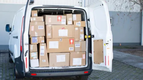 Getty Images A white delivery van with the rear doors open showing that it is full of packages.