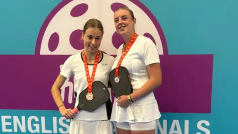 Charlotte Pressley From left to right, Charlotte Pressley and Mollie Knaggs in autumn 2025 with their bronze medals. They both have light brown hair, pulled back from their face, are wearing white tops and shorts and holding up their paddles with their medals around their necks and the metal resting on the paddles. Behind them is a wall saying English finals in capitals. 