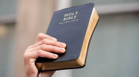 A hand holds the Holy Bible 