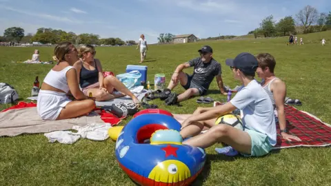 PA Media People sit in a park in Yorkshire