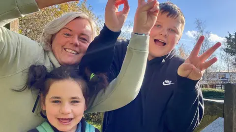 Handout Nathalie is pictured with her son and her daughter Penny. They are looking into the camera smiling and holding up peace signs. 