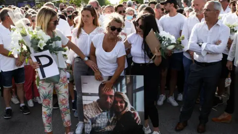 Getty Images Veronique Monguillot holding a picture of her dead husband