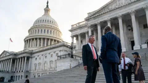 Kent Nishimura Republican Senator Tommy Tuberville talks with Democrat Raphael Warnock outside the Senate side of the U.S. Capitol