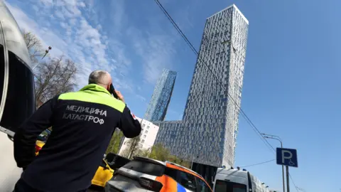 An emergency doctor looks at a damaged high-rise building