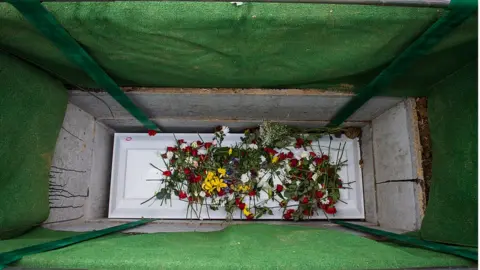 Washington Post via Getty Images Casket lowered into grave