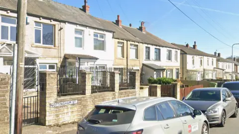 Google A residential street with cars parked outside terraced houses