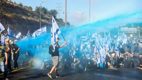 Reuters Protesters are sprayed from a water cannon on a highway near Jerusalem (11/07/23)
