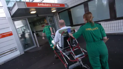 BBC Ambulance crew taking a patient on a stretcher into a hospital emergency department