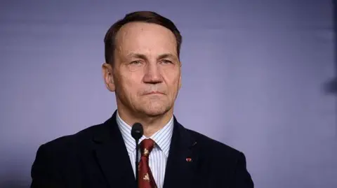 Getty Images Ministro de Relaciones Exteriores polacos Radoslaw Sikorski frente a un micrófono, con una chaqueta y corbata roja