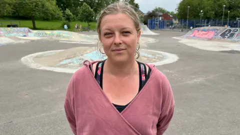 Kat Macaulay. She is pictured at St George's Park in Bristol. She is wearing a pink jacket and a black top underneath. She is looking at the camera and smiling.