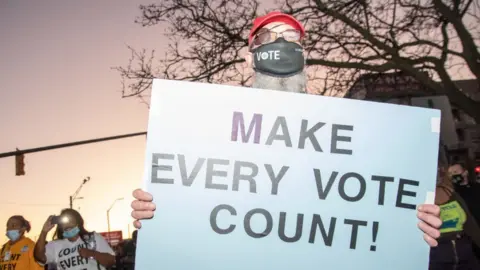 Getty Images A protester in Michigan holds up a sign that says "Make Every Vote Count"