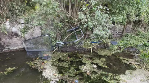 River with debris from bus following crash floating and submerged in the water