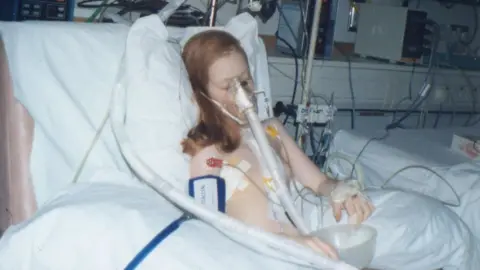 Michelle Crawford Michelle in hospital bed hooked up to machines.