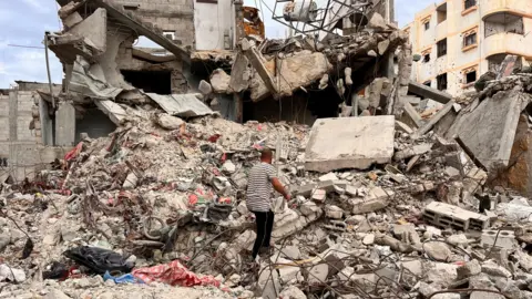 Reuters A man searches through the rubble of a house in Khan Younis in the Gaza Strip