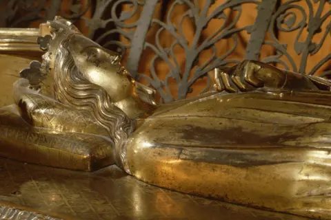 Corbis via Getty Images A gilt-bronze tomb effigy of Queen Eleanor of Castile on her tomb. It depicts a medieval queen laid at rest on her back with long hair and a crown.