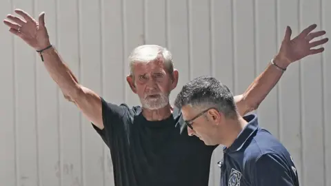 PA Media David Hunter has his arms stretched as if waving