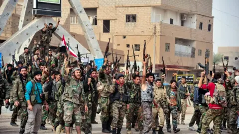 AFP Handout picture from official Syrian Arab News Agency on November 21, 2017 shows members of the pro-Syrian government forces in a public square in the Syrian border town of Albu Kamal.