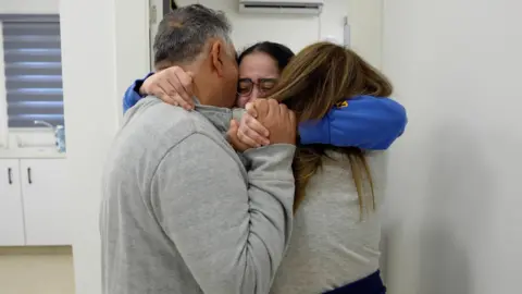 Reuters Liri Albag tightly embracing her parents who are wearing grey tops.