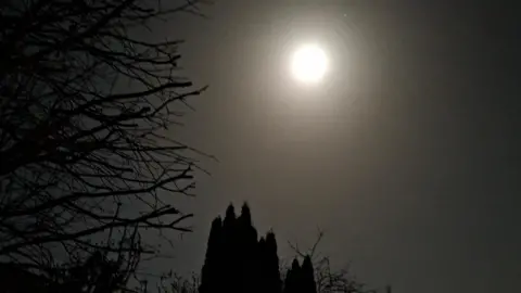Weather watcher/Freeasabird A bright glow in the dark sky over the silhouette of a church.