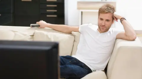 Getty Images Relaxed man watching television smiles contentedly - stock photo