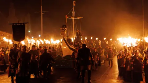 EPA-EFE/REX/Shutterstock Members of the Up Helly Aa festival's 'Jarl Squad' carry flaming torches through the streets of Lerwick, Shetland Islands, Britain, 28 January 2025.