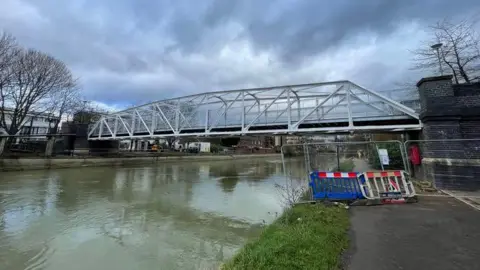 A view of the bridge on an overcast day. There are some barriers on the towpath.