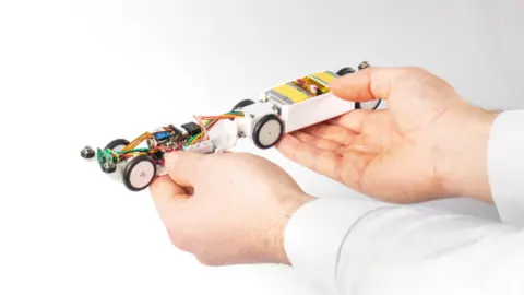 UKAEA ‘PipeINEER’ small autonomous robot held in operator's hand.