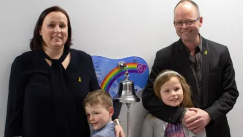 Family Carter with his sister and mum and dad in a corridor at Birmingham Children's Hospital 