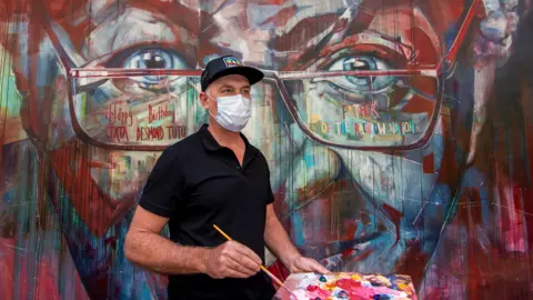 Getty Images A wall mural of Archbishop Desmond Tutu is restored by the artist Brian Rolfe in Cape Town, South Africa - 7 October 2021