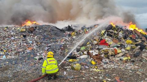 Firefighters damp down burning rubbish at Calne near Wiltshire