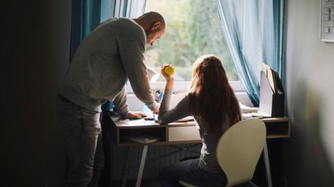 Father helping daughter study at home (stock image)