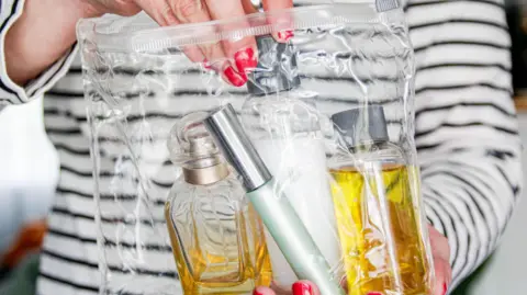 Getty Images Woman putting perfume and mascara in a clear plastic bag