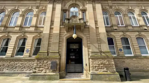 A large beige building with pillars on either side of a large doorway