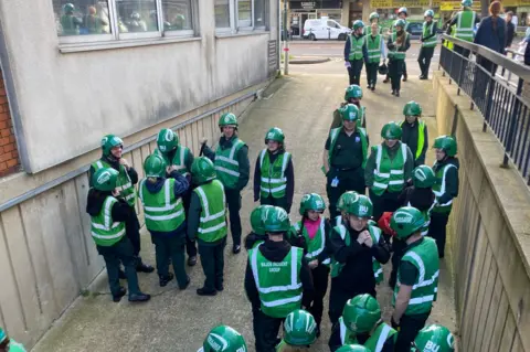 BU Paramedics gather outside the car park in green vests and helmets.
